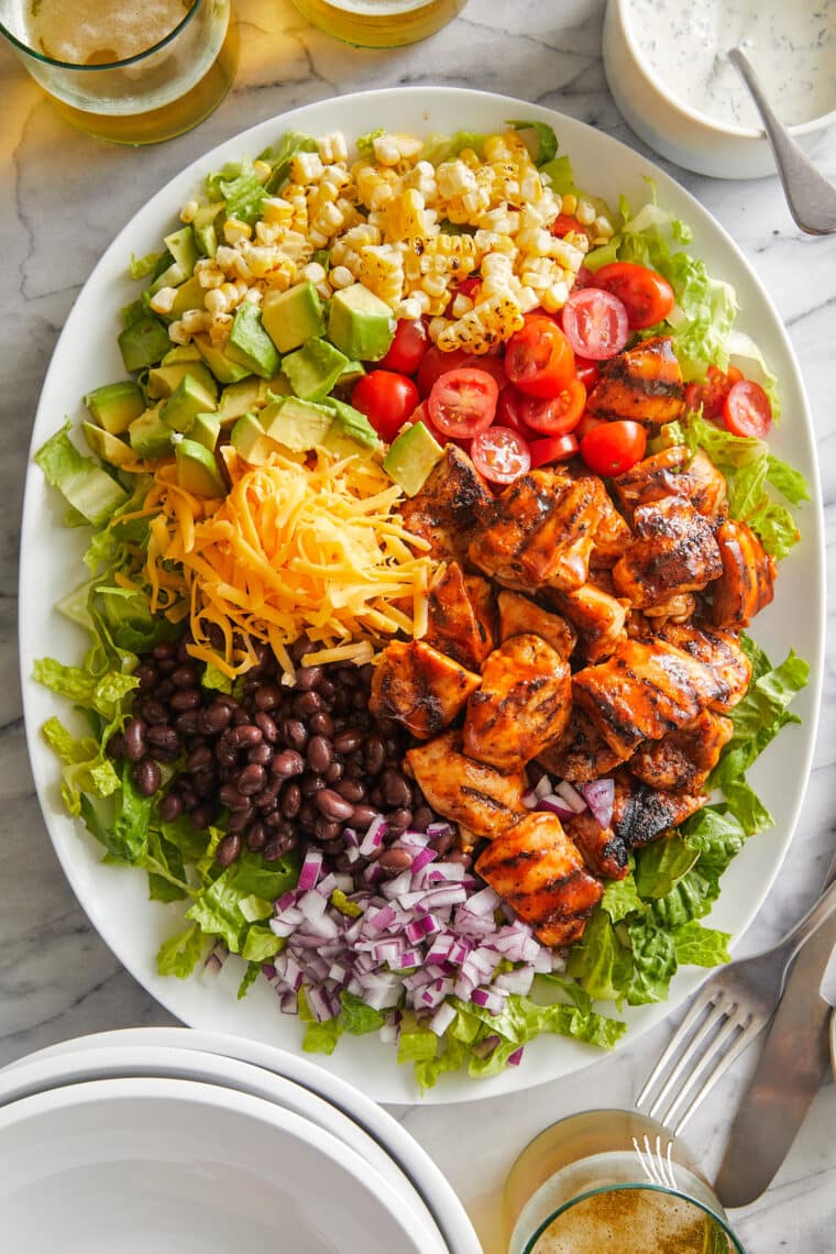 BBQ Chicken Salad - Smoky BBQ chicken, corn, tomatoes, black beans, avocado + cheese drizzled with homemade Ranch. An instant family favorite!