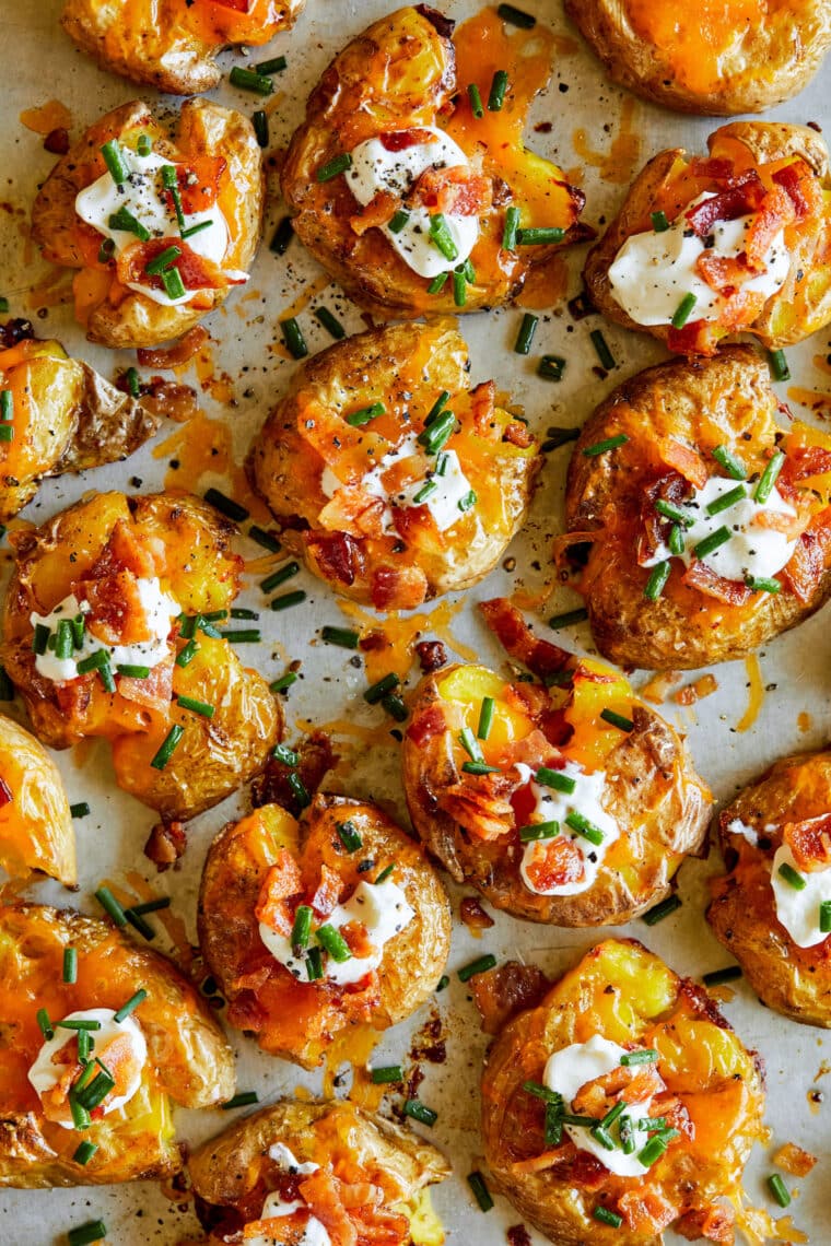 Loaded Smashed Potatoes - SUPER CRISPY smashed potatoes topped with sour cream, bacon + chives. The easiest most perfect bite-sized appetizer.