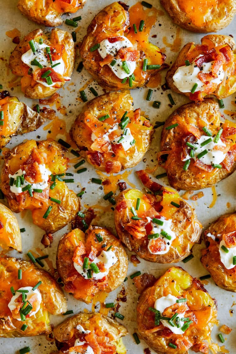 Loaded Smashed Potatoes - SUPER CRISPY smashed potatoes plus sour cream, bacon + chives.  The lightest and perfect bite-sized appetizer.