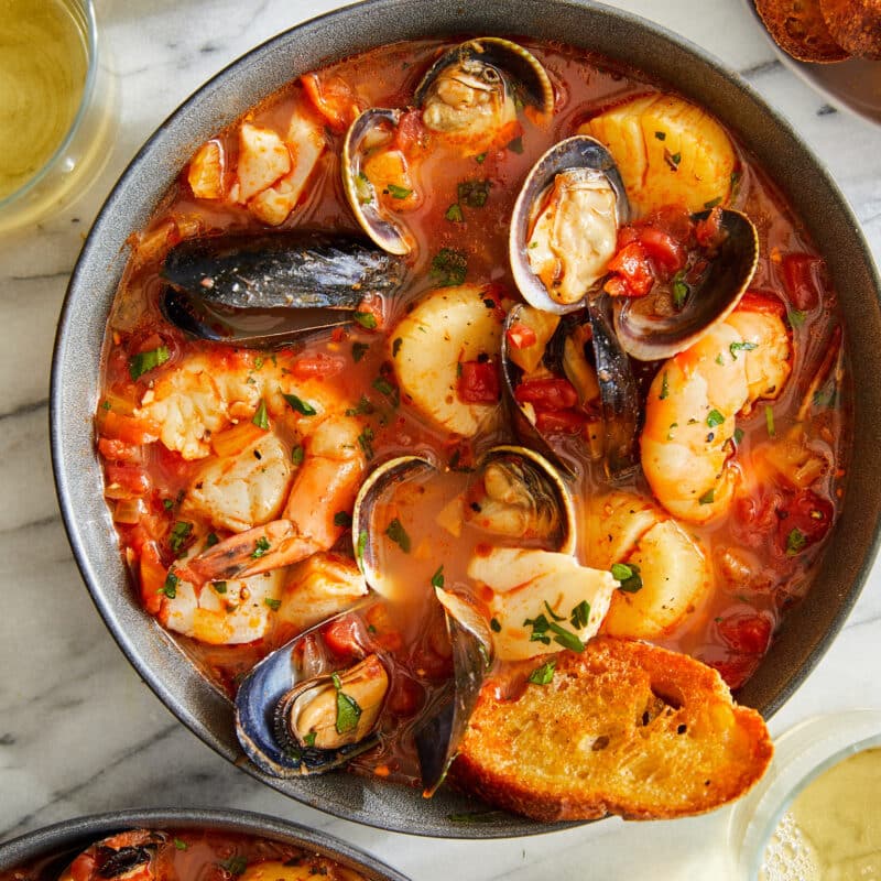 A Cioppino (seafood stew) made with clams, mussels, cod, shrimp and scallops served with slices of freshly toasted baguette.