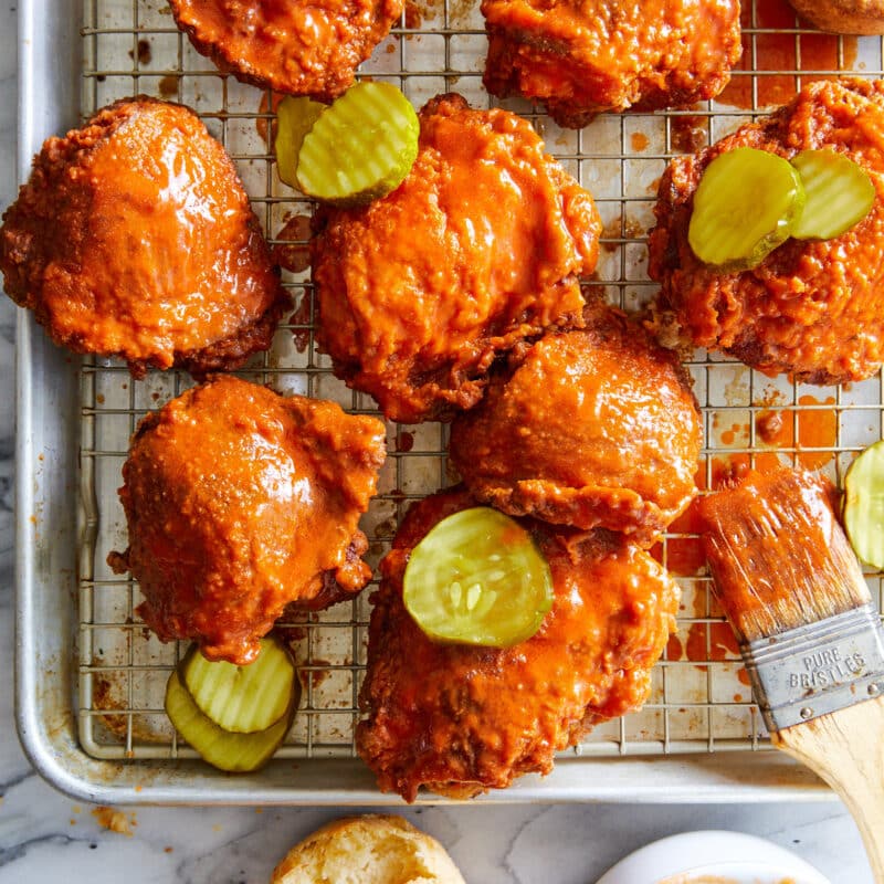 Crisp-fried chicken basted with a cayenne-pepper buttermilk mixture, ready to be served with biscuits and dill pickle.