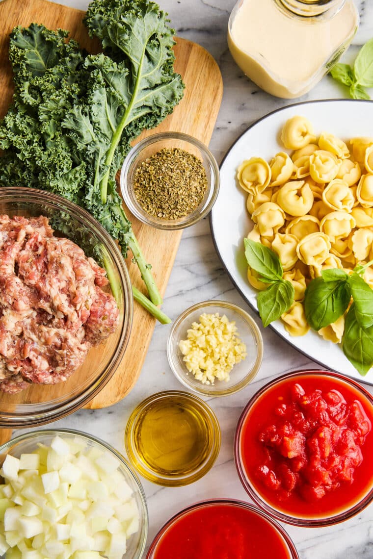 Slow Cooker Tortellini Soup - With crumbled sausage, tomatoes, pillowy cheese tortellini + leafy greens in a velvety, creamy broth. SO GOOD!