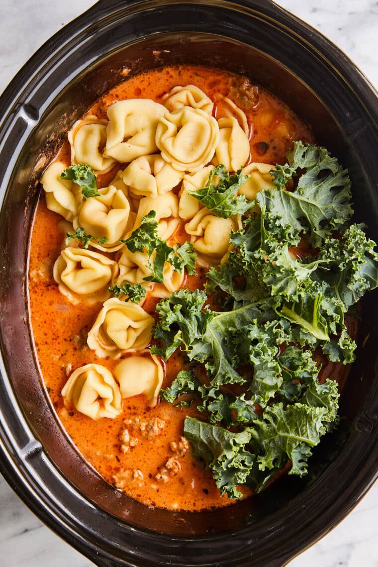 Slow Cooker Tortellini Soup - With crumbled sausage, tomatoes, pillowy cheese tortellini + leafy greens in a velvety, creamy broth. SO GOOD!