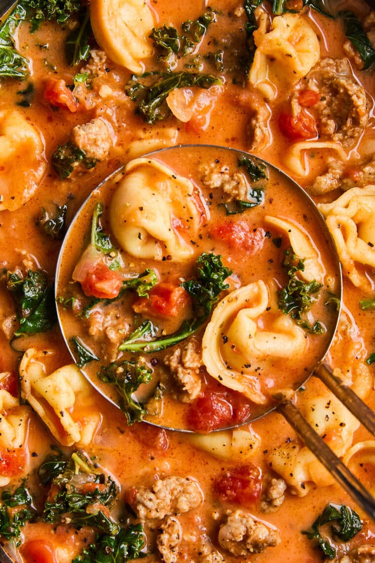 Slow Cooker Tortellini Soup - With crumbled sausage, tomatoes, pillowy cheese tortellini + leafy greens in a velvety, creamy broth. SO GOOD!