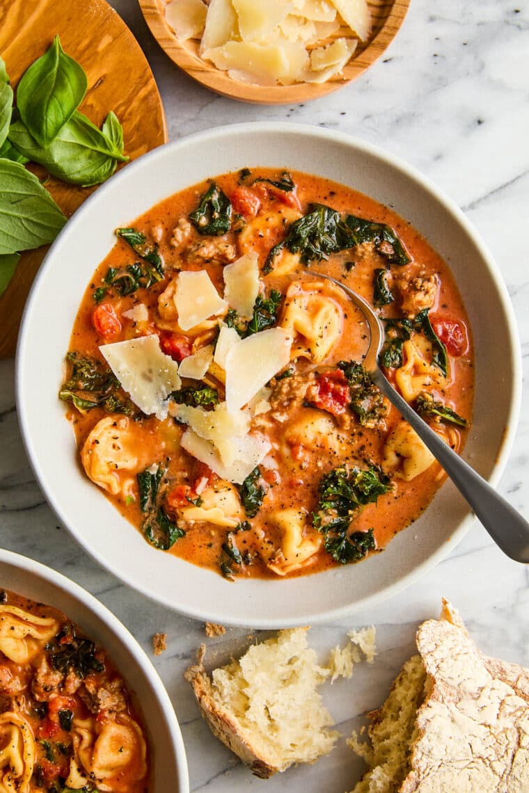 Slow Cooker Tortellini Soup - With crumbled sausage, tomatoes, pillowy cheese tortellini + leafy greens in a velvety, creamy broth. SO GOOD!